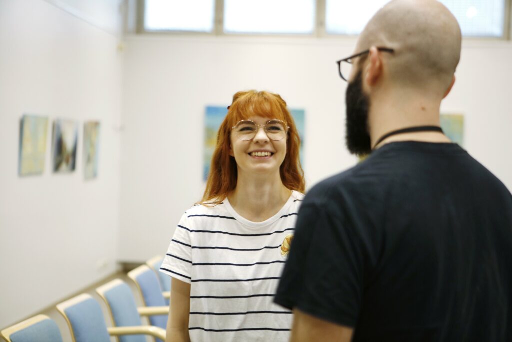 Nainen hymyilee edessään seisovalle miehelle.