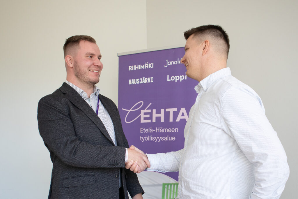 Yritysneuvoja ja yritysasiakas kättelevät toisiaan hymyillen.